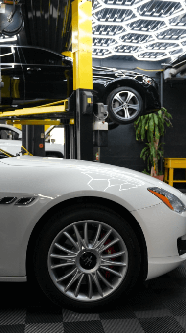 A side view of two cars, high-lighting the tires, inside the EG Auto Center Shop in Dayton, NJ.