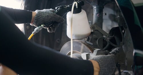 What You Should Know About Brake Repair & Service | Image of an auto mechanic replacing brake fluid on a vehicle.