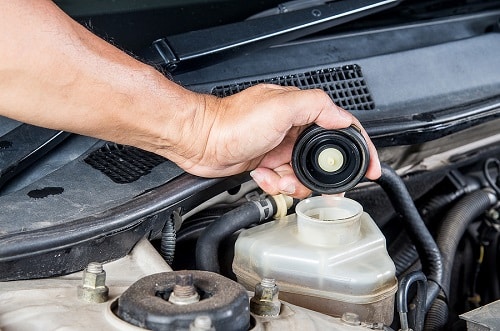 Fluid Excahnge | EG Auto Center in Dayton, NJ. Image of a mechanic checking brake fluid inlet as part of car maintenance.