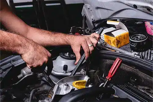 Engine Repair, Rebuild, & Replacement | EG Auto Center in Dayton, NJ. Closeup image of a mechanic’s hand with spanner repairing a car engine.