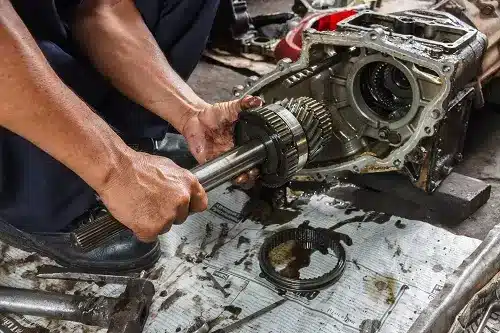 Repair, Rebuild, or Replace Transmission - What's the Best Option? | EG Auto Center in Dayton, NJ. Image of a car mechanic working in auto repair shop performing transmission repair or replacement.