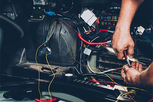A mechanic checking or repairing a car’s wiring. Concept image of “Auto Electrical System Repair in Dayton, NJ” | EG Auto Center.